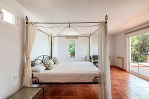 Ein Bett mit Baldachin, ein Fenster mit Blick auf Grünflächen und ein Balkon mit Geländer.