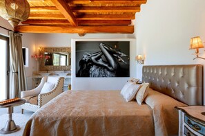 Ein Schlafzimmer mit einem großen Bett, einem Sessel, einem Schreibtisch und einem Spiegel.