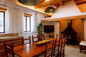 Ein Essbereich mit Holztisch, Stühlen, einem Fernseher und einem Kamin aus Ziegelsteinen.
