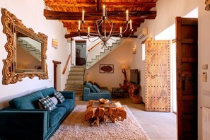 Ein Wohnzimmer mit einer Kandelaber, einem großen Spiegel, einem Sofa, einem Couchtisch und einer Holztür.