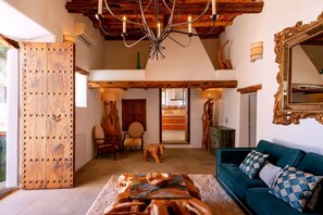 Ein geräumiger Wohnbereich mit Holztür, einer Chandelüster, einer Couch und einem Esstisch.