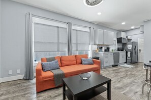 Ein modernes Wohnzimmer mit einer Couch, einem Couchtisch und einer Küche im Hintergrund.
