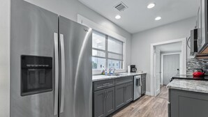 A modern kitchen with stainless steel appliances, grey cabinetry, a window, and a red kettle on the counter. - Entire Midtown 4plex - Gated Parking - Rail to NRG (Houston)