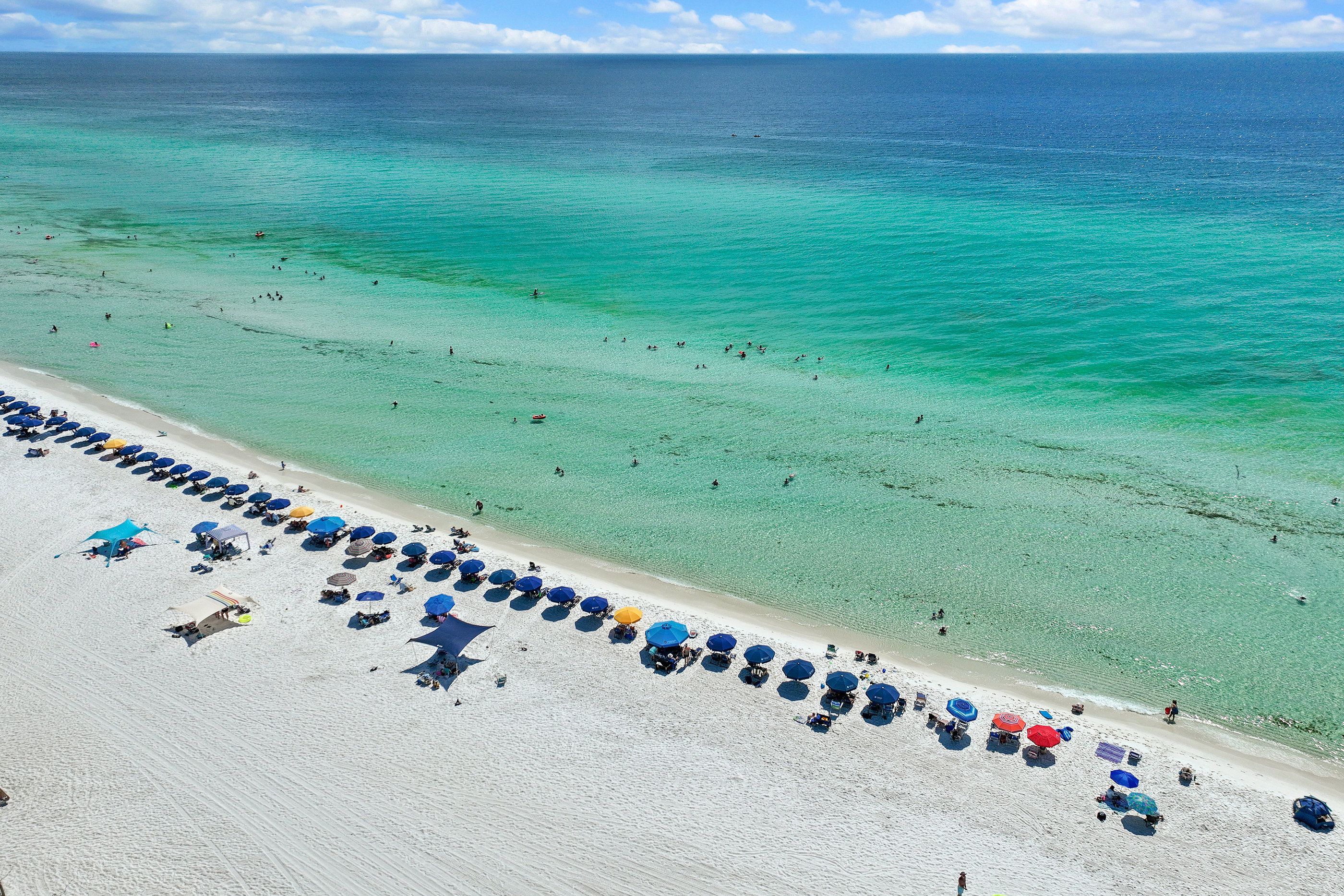 Une plage bordée de rangées de parasols et de chaises longues.