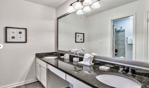 Een badkamer met twee wastafels, een grote spiegel en een douche in de achtergrond.