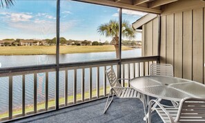 A covered outdoor area with a table and chairs, overlooking a body of water and a golf course. - Seascape 3 BD/3 BA condo- 2 mins to the beautiful white sand beach! Sleeps 7 (Miramar Beach)