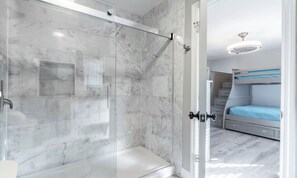 A modern bathroom with a glass shower enclosure and a visible door leading to a bedroom with a bunk bed. - Seascape 3 BD/3 BA condo- 2 mins to the beautiful white sand beach! Sleeps 7 (Miramar Beach)