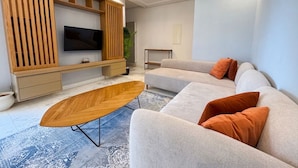Ein modernes Wohnzimmer mit einem Ecksofa, einem Couchtisch, einem Fernseher und Einbauschränken.