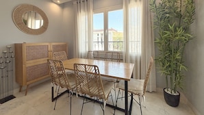 Ein Essbereich mit Holztisch, Korbstühlen, einem Spiegel und einem Blumentopf.
