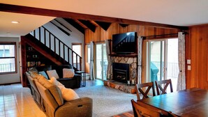 A living room with a fireplace, a sofa, a dining table, and a staircase. - Peaceful 3BR Sunriver Home Close to Sharc & Village (Bend)