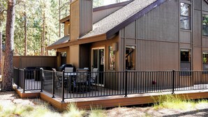 A modern two-story building with a deck, outdoor seating, and a view of the surrounding forest. - Peaceful 3BR Sunriver Home Close to Sharc & Village (Bend)
