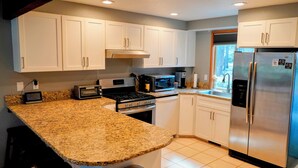 A kitchen with white cabinets, a granite countertop, a stainless steel refrigerator, a microwave, a stove, and a window. - Peaceful 3BR Sunriver Home Close to Sharc & Village (Bend)