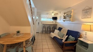 Ett kompakt bostadsutrymme med en matplats, en soffa, en TV och en takfläkt.
