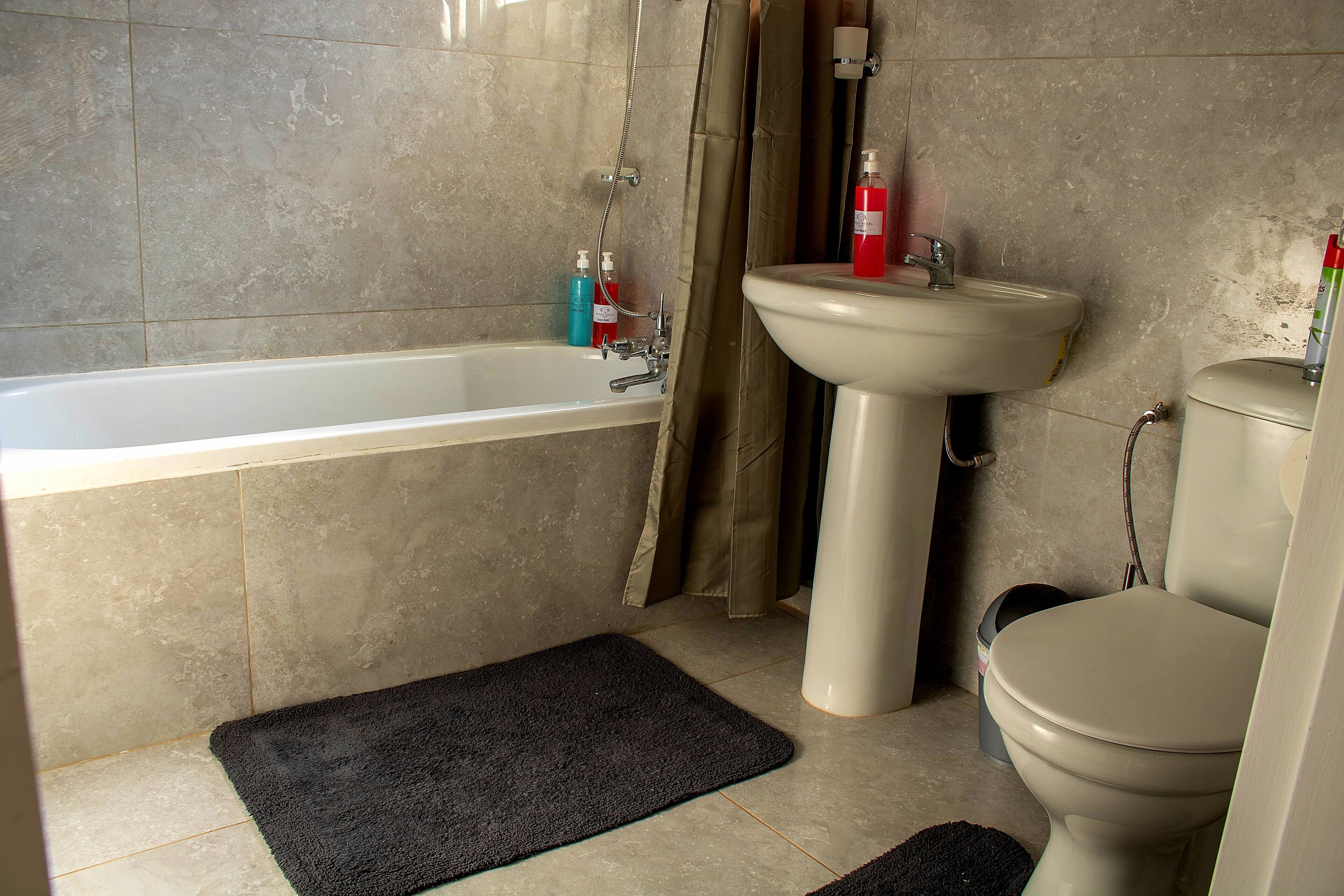 A bathroom with a bathtub, sink, toilet, and shower curtain.
