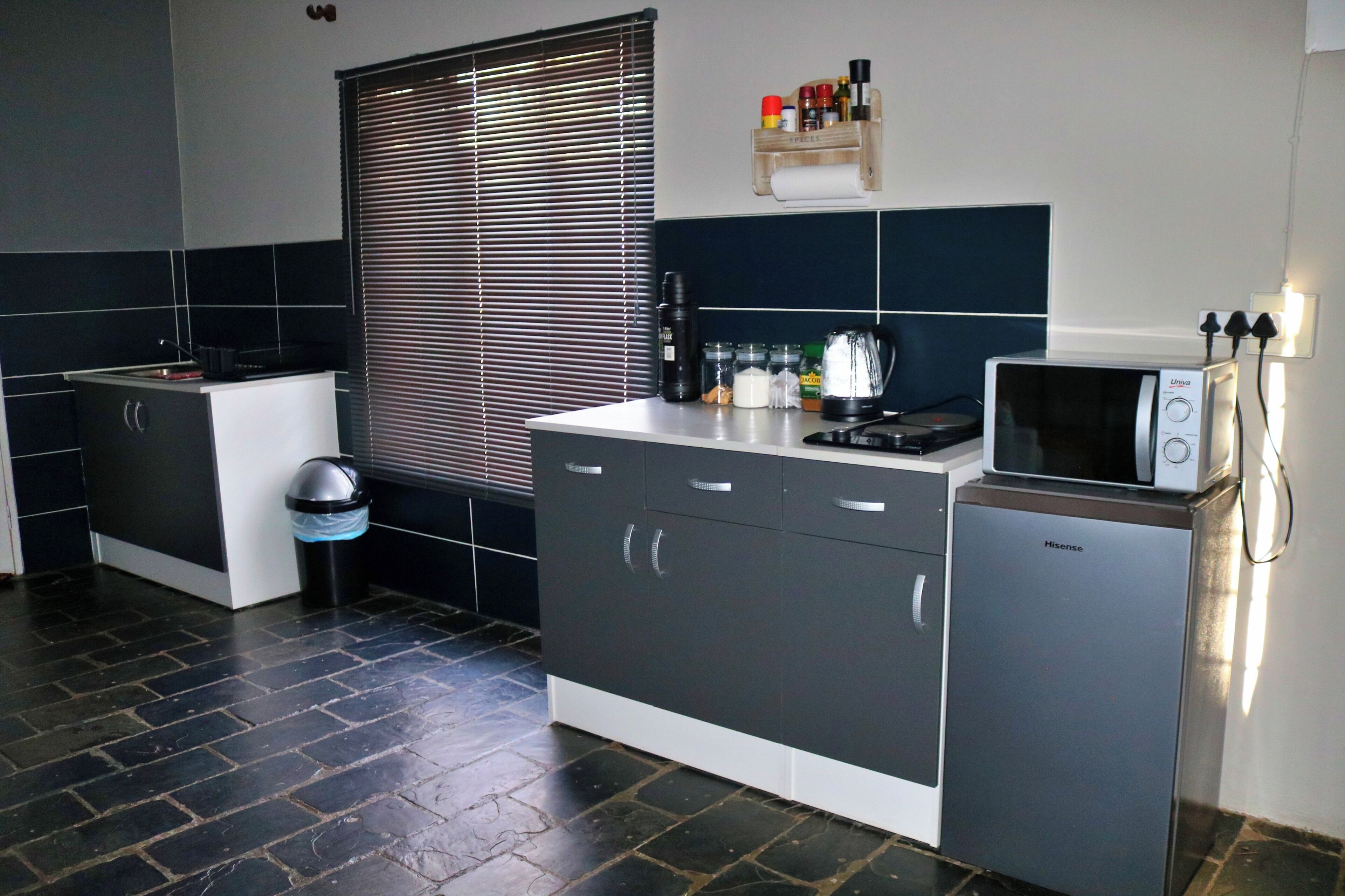 A modern kitchen with a microwave, a small refrigerator, and a trash bin.