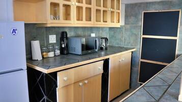 A kitchen with a refrigerator, microwave, coffee maker, and cabinets.