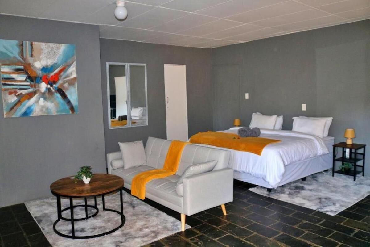 Un dormitorio moderno con una cama, un sofá, una mesita y un cuadro en la pared.