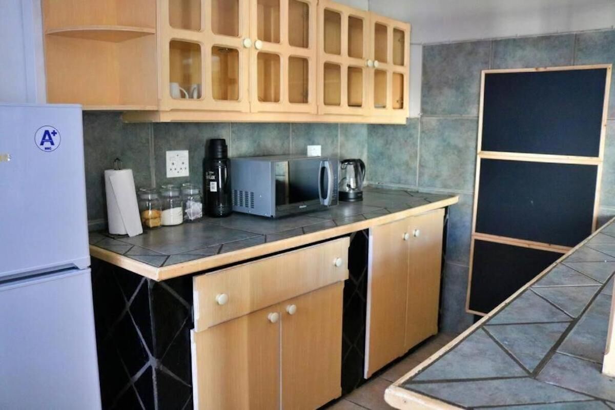 Cocina compacta con refrigerador, microondas, cafetera y gabinetes.