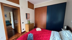 Ein Schlafzimmer mit Bett, Kommode, Spiegel und Kleiderschrank.