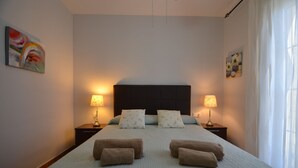 Ein Schlafzimmer mit einem großen Bett, zwei Nachttischen mit Lampen, einer Kopfteil und einem Bild an der Wand.