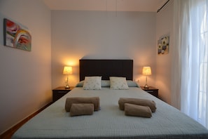 A bedroom with a large bed, two bedside tables with lamps, a headboard, and a painting on the wall. - Playa Grande 23 - Two Bedroom Apartment, Sleeps 5 (Punta del moral)