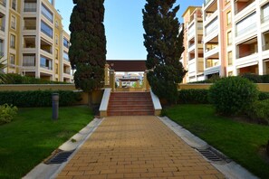 A pathway leading to a building with multiple balconies, surrounded by greenery and a clear sky. - Playa Grande 23 - Two Bedroom Apartment, Sleeps 5 (Punta del moral)