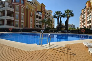 A swimming pool with a tiled deck, surrounded by multi-story buildings with balconies. - Playa Grande 23 - Two Bedroom Apartment, Sleeps 5 (Punta del moral)