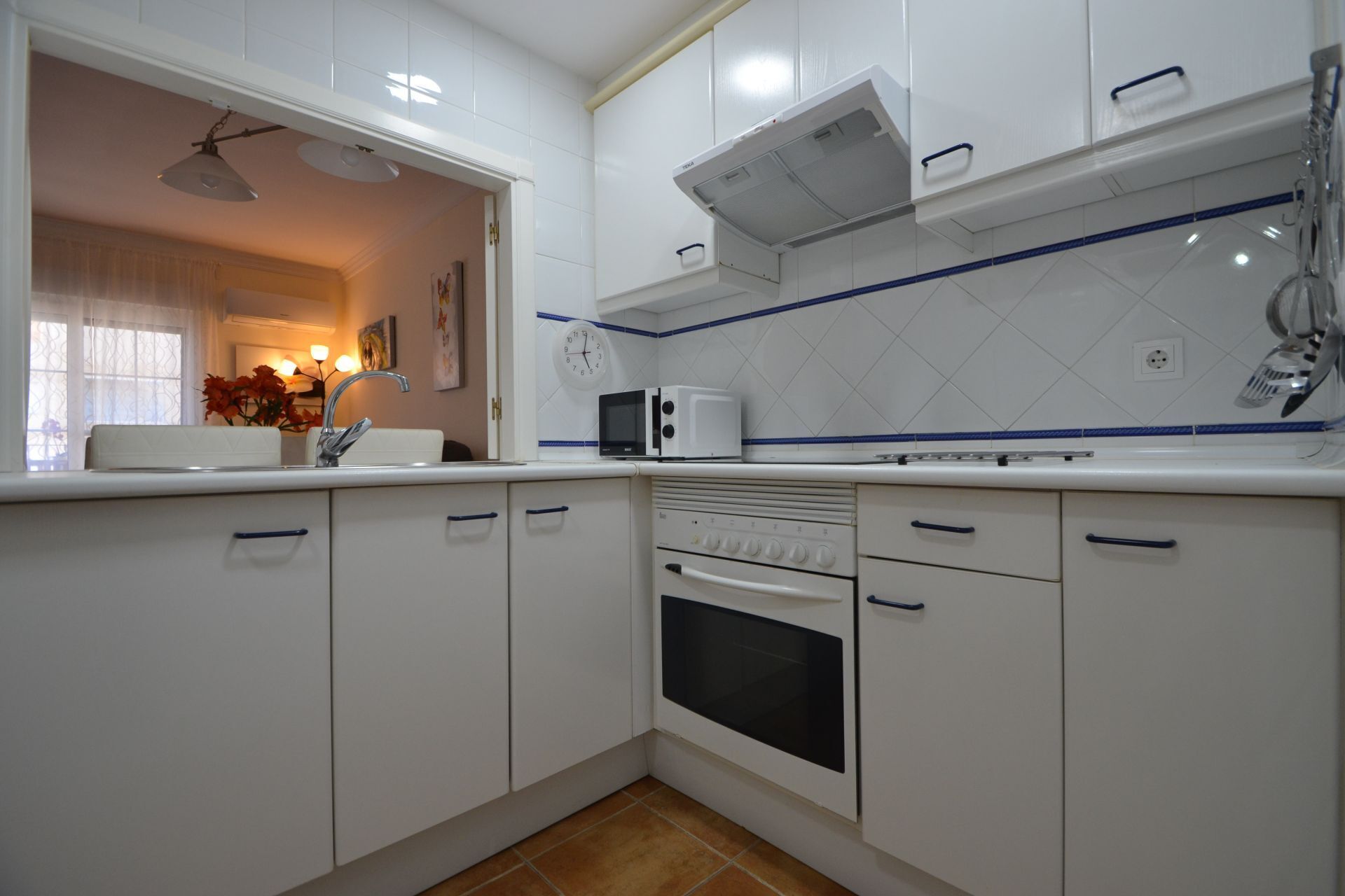 A kitchen with white cabinets, a microwave, an oven, and a sink.
