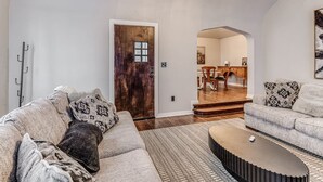 Ein Wohnzimmer mit Sofa, Couchtisch und einer Holztür, die in einen Essbereich führt.