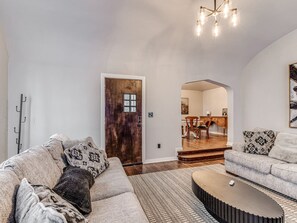 Ein Wohnzimmer mit Sofa, Couchtisch und einer Holztür, die in einen Essbereich führt.