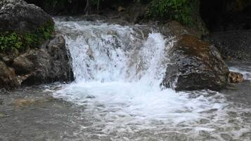 Ein Wasserfall in einer naturnahen Umgebung mit Felsen und viel Grün.