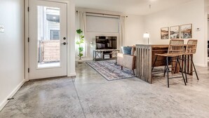 Uma sala moderna com sofá, mesa de centro e área de jantar com cadeiras.