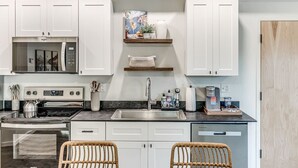 Uma cozinha moderna com armários brancos, eletrodomésticos de aço inoxidável e micro-ondas embutido.