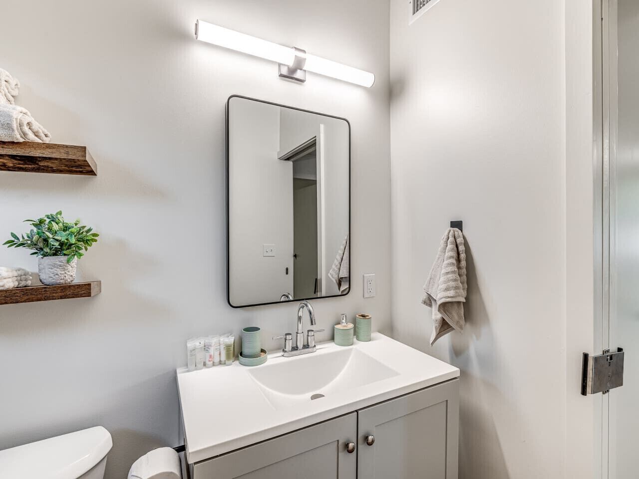 Une salle de bain moderne avec un lavabo blanc, un miroir et un porte-serviettes.