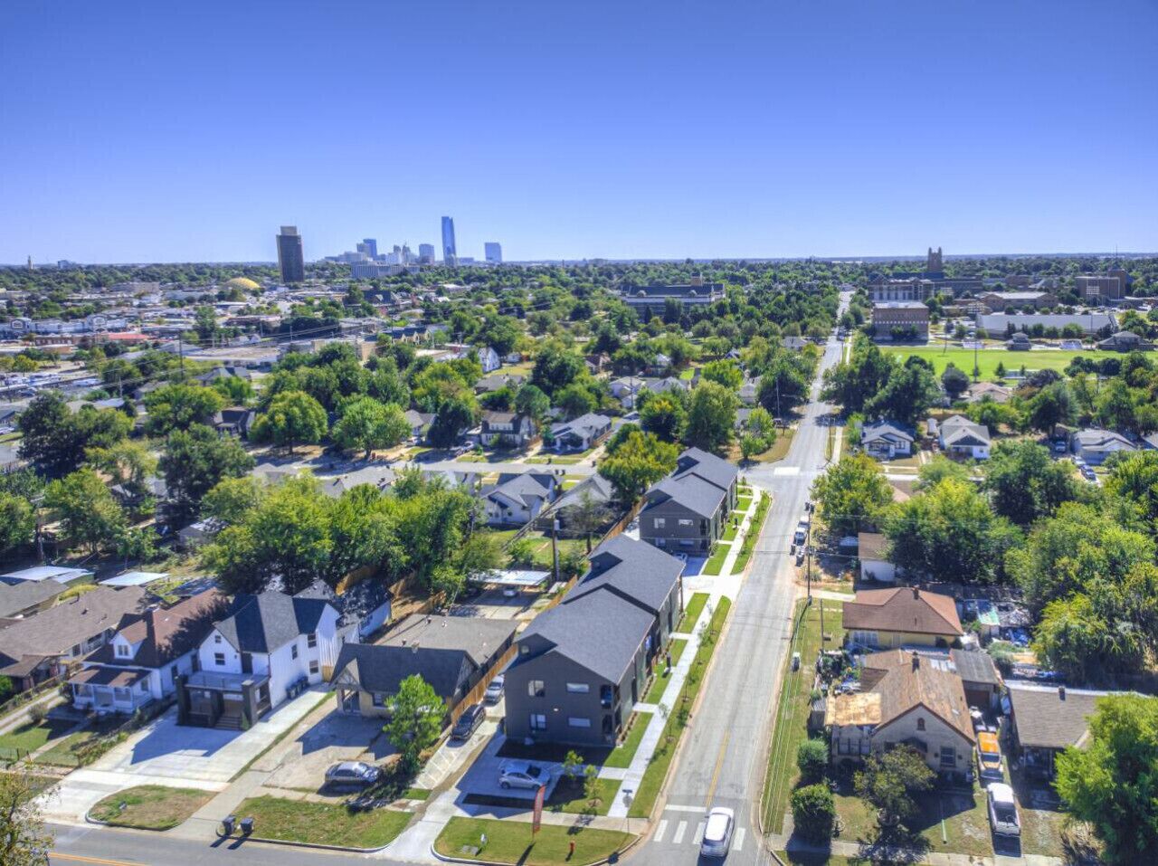 Vista aérea de un barrio residencial con casas, calles y un horizonte urbano lejano.