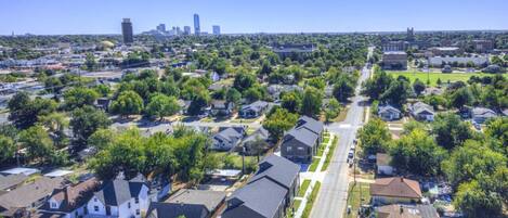 Vista aérea de un barrio residencial con casas, calles y un horizonte urbano lejano.