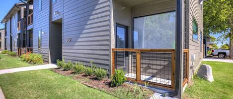A modern two-story building with a well-maintained lawn, a covered outdoor seating area, and a visible garage.