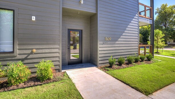 A modern two-story building with a grey exterior, a visible door, and a small porch area. - Midtown OKC 1Bed Hideaway (Oklahoma City)