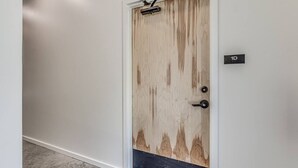 A door with a wooden panel design, a black threshold, and a small sign with the number '1D'. - Midtown OKC 1Bed Hideaway (Oklahoma City)