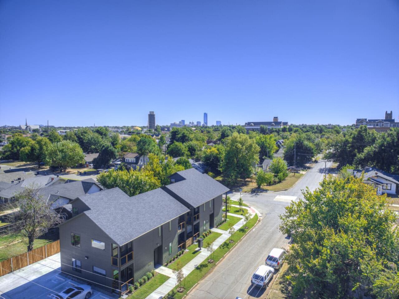 Zona residencial con casas modernas, cielo despejado y un horizonte urbano distante.