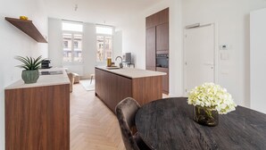 Eine moderne Küche mit Holzausstattung, einer zentralen Kochinsel und einem Essbereich mit rundem Tisch.