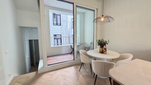 Eine moderne Wohnung mit Balkon, einem Essbereich inklusive Tisch und Stühlen sowie einer Pendelleuchte.