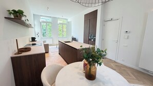 Eine moderne Küche mit Kochinsel, Holzschränken und einem Essbereich mit rundem Tisch.