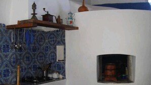 Eine Küche mit blau gemustertem Fliesenspiegel, einer hängenden Topfhalterung und einem kleinen, in die Wand eingelassenen Backofen.