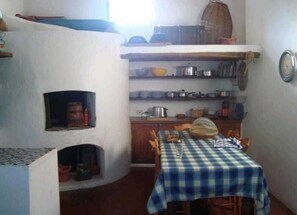 Eine KĂŒche mit Kamin, HolzschrĂ€nken und einem Tisch mit kariertem TischlĂ€ufer.
