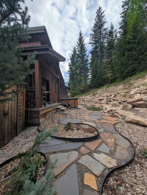 Una casa moderna de madera con un sendero de piedra que lleva a una terraza de madera.