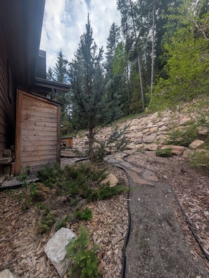 Eine Holzhütte mit einem Steinpfad, der zu einer kleinen Holzkonstruktion führt.