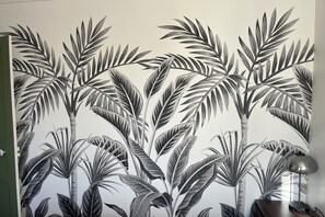 Ein Zimmer mit einer großen Wandmalerei von tropischen Pflanzen, einer Holzvertäfelung und einer Stehlampe.