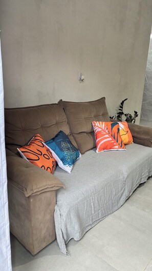 A brown sofa with a grey throw blanket and three pillows with various patterns. - Loft with private pool in Ubatuba / 10 minutes from Praia Grande-Tenório-Toninha (Ubatuba)