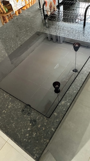 Eine Küche mit schwarzem Arbeitsplatz, einem Spülbecken und einem Metallregal.